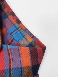 Macro shot of British plaid fabric showing red, blue and orange weave texture and stitching