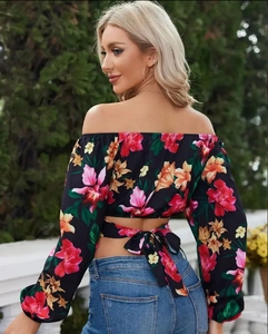Dettaglio di un crop top a stampa tropicale con schiena scoperta e fiocco annodato sul retro