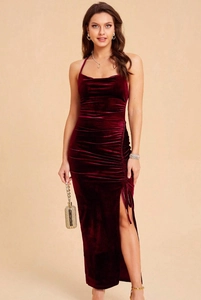 Detailed texture of burgundy velvet dress showing side slit and ruching folds