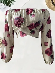 Dettaglio della camicetta floreale con spalle scoperte, stampa a rose e vita incrociata