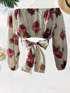 Dettaglio del crop top bianco con stampa di rose, scollo a barchetta e fiocco sull'orlo