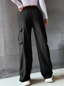 Dettaglio della vita alta elastica e delle grandi tasche cargo sui pantaloni neri