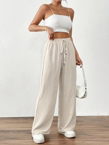 Close-up of beige wide-leg trousers featuring elastic drawstring waist and pleated fabric