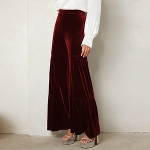 Detailed close-up of burgundy velvet high-waisted wide-leg trousers with tiered ruffles