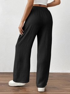Detail of high waisted black wide leg pants showing pleated texture and elastic waistband