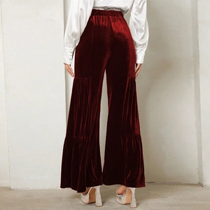 Detail of high-waisted velvet wide leg trousers in burgundy with tiered layering