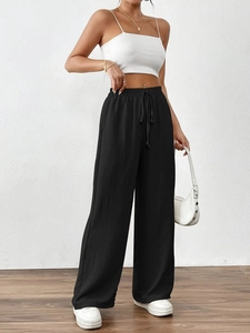 Detail view of black wide-leg trousers featuring elastic drawstring waist and textured fabric