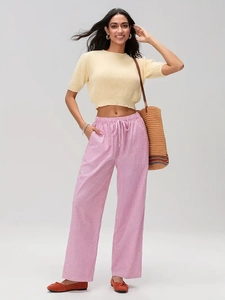 Détail du pantalon large à rayures roses avec cordon de serrage et crop top en maille beige
