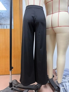 Rear view of black high-waisted wide-leg trousers with sleek tailoring and matte drape