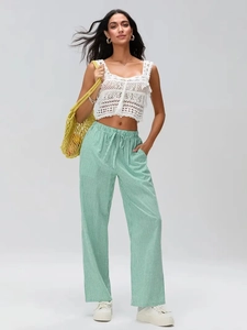 Détail du pantalon large à rayures vertes à taille haute avec crop top au crochet blanc