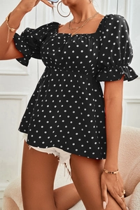 Detailed view of the square neckline and puffed sleeves on the black polka dot blouse