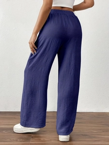 Detail view of navy blue wide-leg trousers with pleated texture and elastic waist back