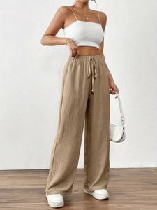Detail of high-waisted wide-leg trousers featuring elastic drawstring waist and wrinkled texture