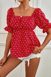 Detail of red polka dot top featuring square neckline and puff sleeves with ruffles