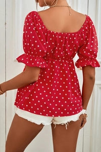Detail of red polka dot top featuring puff sleeves and elastic shirred waist design