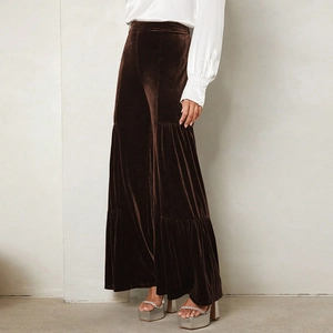 Detail of high-waisted brown velvet wide-leg trousers with elegant tiered ruffle layers