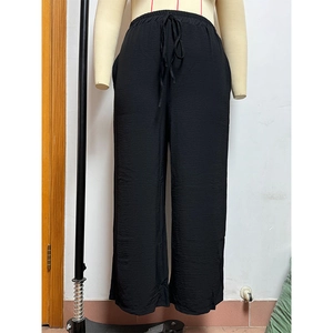 Detail view of black wide-leg trousers featuring elastic drawstring waist and textured fabric