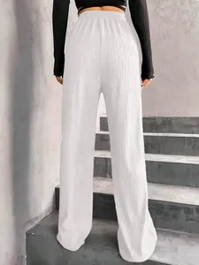Détail du pantalon plissé blanc à taille haute avec ceinture élastique et jambe large