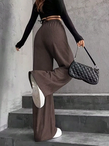 Texture détaillée du pantalon plissé marron à taille haute montrant le drapé et le tissu