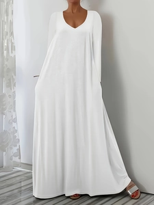 Detail view of the deep V-neckline and loose long sleeves on a minimalist white dress