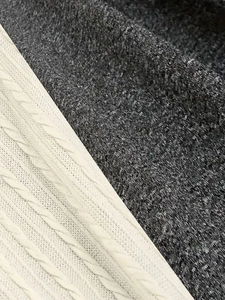 Elegant knit dress closeup showing cream cable knit texture and dark grey heather fabric