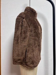 Close-up of deep brown fleece jacket showing side pocket and thick plush texture