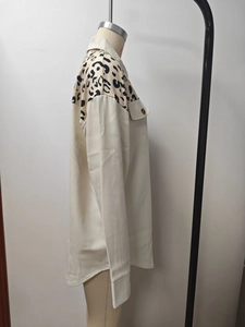 Detailed view of leopard print shoulder patch on a cream button-up long sleeve jacket