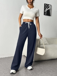 Detail of high-waist navy wide-leg trousers featuring white drawstring and side pockets