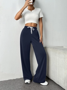 Detail of dark blue high-waisted wide-leg sweatpants with white contrast drawstring