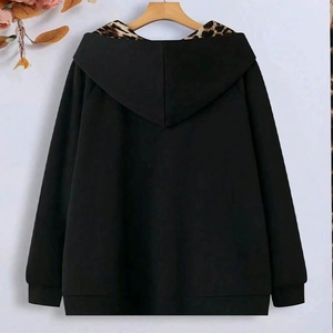 Detail view of black oversized hoodie featuring leopard print lining inside the hood