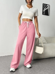 Close-up of pink wide-leg sweatpants featuring elastic high waist and white drawstrings
