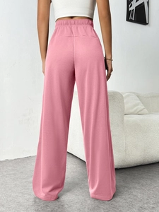 Detail view of pink high-waist wide-leg trousers showing elastic waistband and fabric drape
