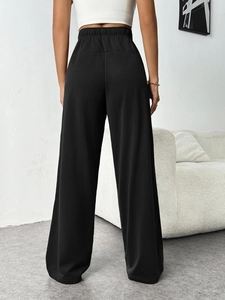 Rear view of black high-waisted wide-leg sweatpants with elastic waist on a model