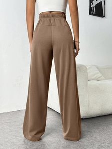 Detail view of coffee brown wide leg trousers with elastic waistband from a back angle