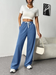 Detail of navy wide-leg sweatpants featuring elastic waist and white contrast drawstring