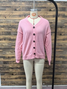 Detail of pink knitted V-neck cardigan with five brown buttons on a wooden background