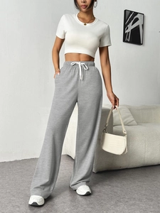 Detail of grey wide-leg lounge pants with elastic waist and white drawstring cord