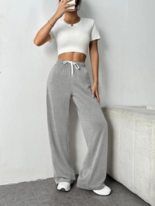 Detail of light grey wide-leg joggers with elastic drawstring waist and soft knit fabric