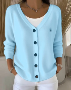 Detail of light blue knit cardigan with V-neck and dark blue buttons for a casual look