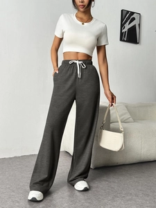 Detail of dark grey wide leg sweatpants with elastic drawstring waist on a model