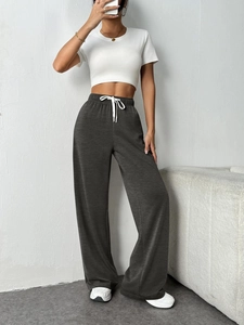 Detail view of dark grey wide-leg sweatpants featuring elastic waist and white drawstring
