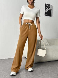 Close-up of brown high-waisted wide-leg sweatpants with drawstring and soft knit texture