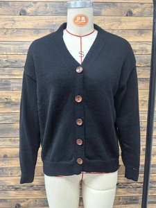 Detail of V-neck black knit cardigan showing brown buttons and soft ribbed texture