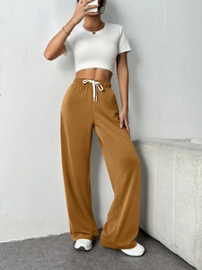 Detail of high-waist tan joggers featuring an elastic waistband and white drawstrings