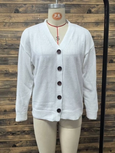 Detail view of the white V-neck knit cardigan with five brown buttons and ribbed cuffs