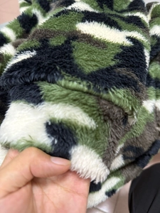 Close-up of thick camouflage plush fabric showing soft texture for winter jackets