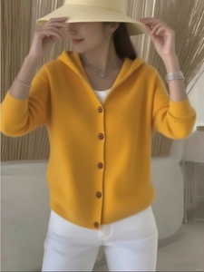 Details der weichen gelben Strickjacke mit Kapuze, braunen Knöpfen und feiner Textur
