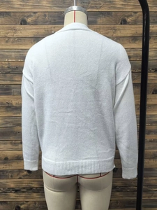Detail view of white knit cardigan back featuring dropped shoulders and ribbed hemline