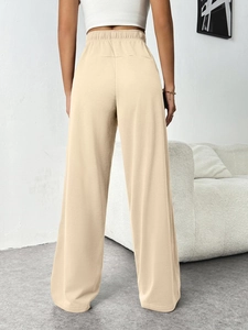 Detail view of the elastic high waist and back seam on light beige wide leg trousers