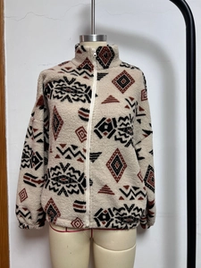 Detailed close-up of ethnic geometric print on cozy beige fleece jacket with full zipper